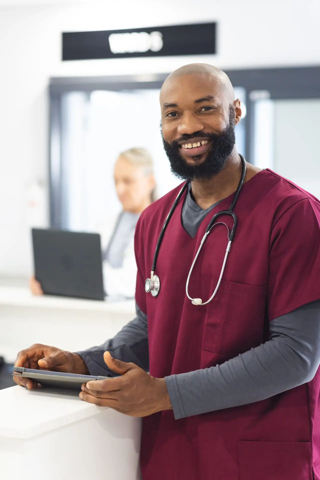 Smiling male doctor holding a tablet at hospital reception