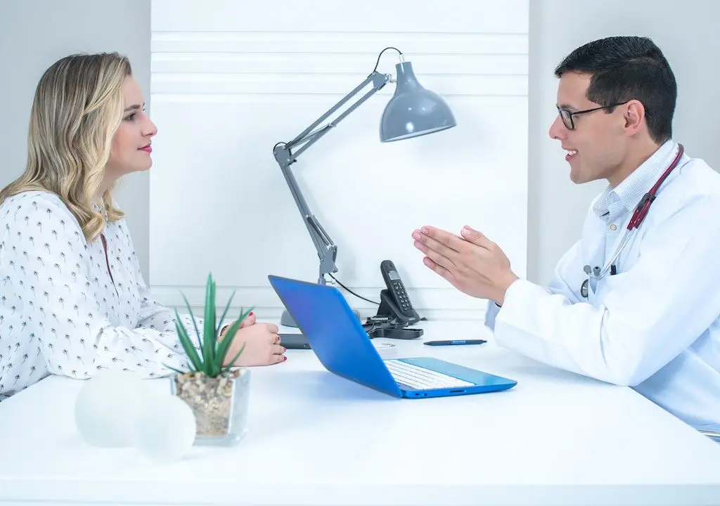 Female patient consulting with a smiling male doctor in a modern clinic setting