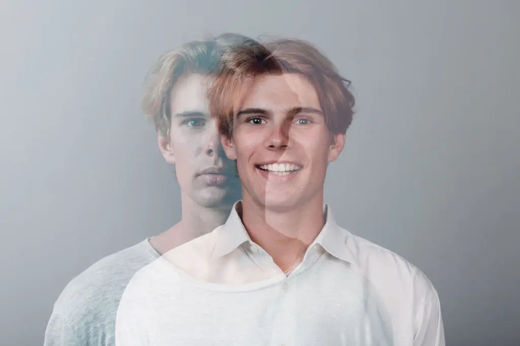A young man with a double exposure effect showing both a serious and a happy expression, symbolizing emotional and mental health balance
