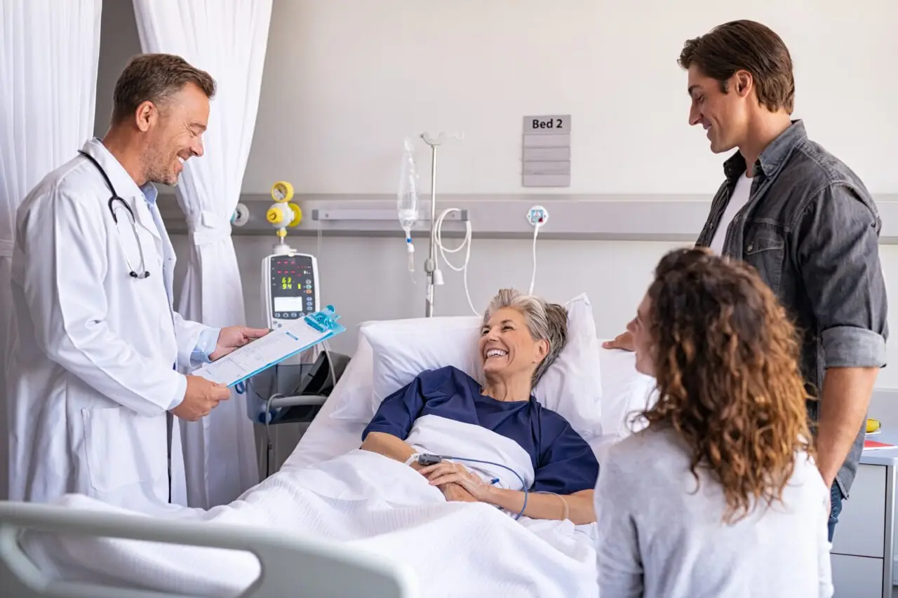Smiling senior patient in hospital bed with family and doctor during recovery