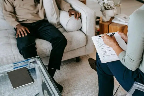 Therapist taking notes during a counseling session with a male patient