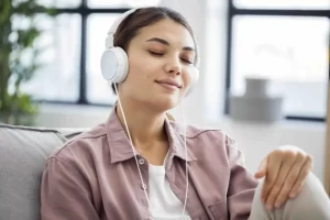 Young woman enjoying music therapy with headphones, eyes closed and relaxed on a couch