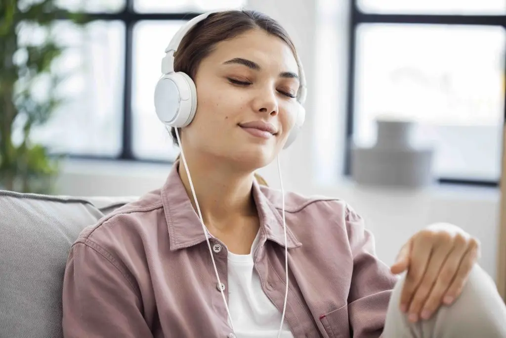 Young woman enjoying music therapy with headphones, eyes closed and relaxed on a couch