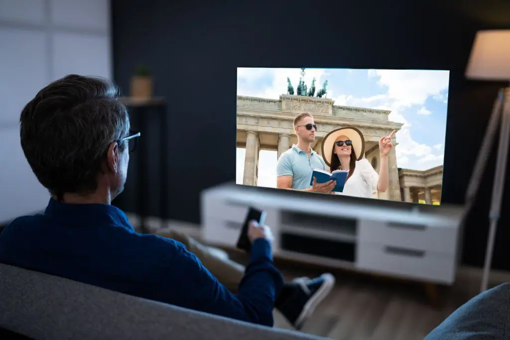 Man watching a true crime documentary on TV featuring tourists at a historic landmark